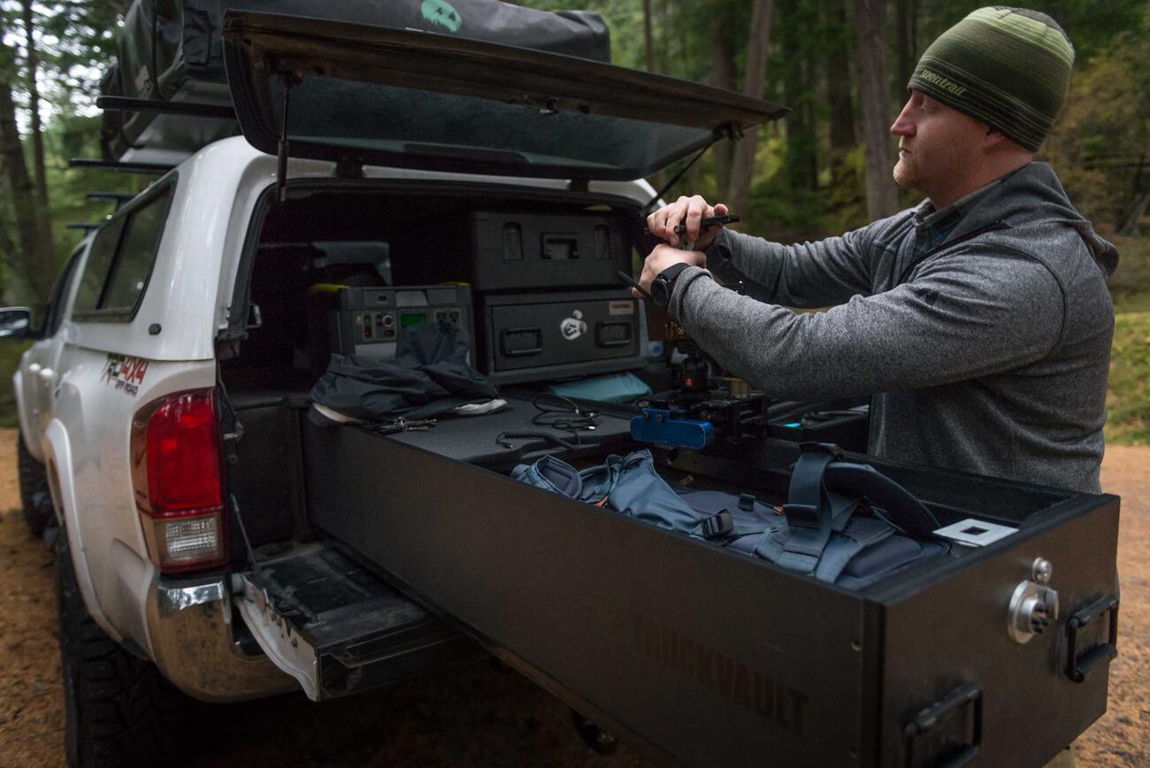 Andy Best taking his camera gear out of a TruckVault in the back of his Toyota Tacoma.