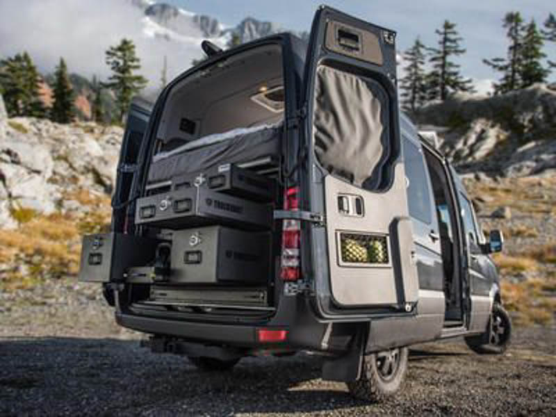 A black Mercedes Sprinter van with a man cooking breakfast on his TruckVault pullout table.