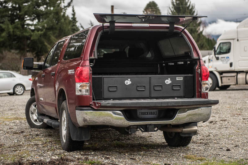 A red Toyota Tundra with a canopy and a TruckVault in the bed