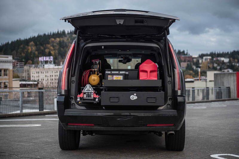 A black Cadillac Escalade roadside assistance vehicle with a TruckVault in the cargo area to protect equipment.