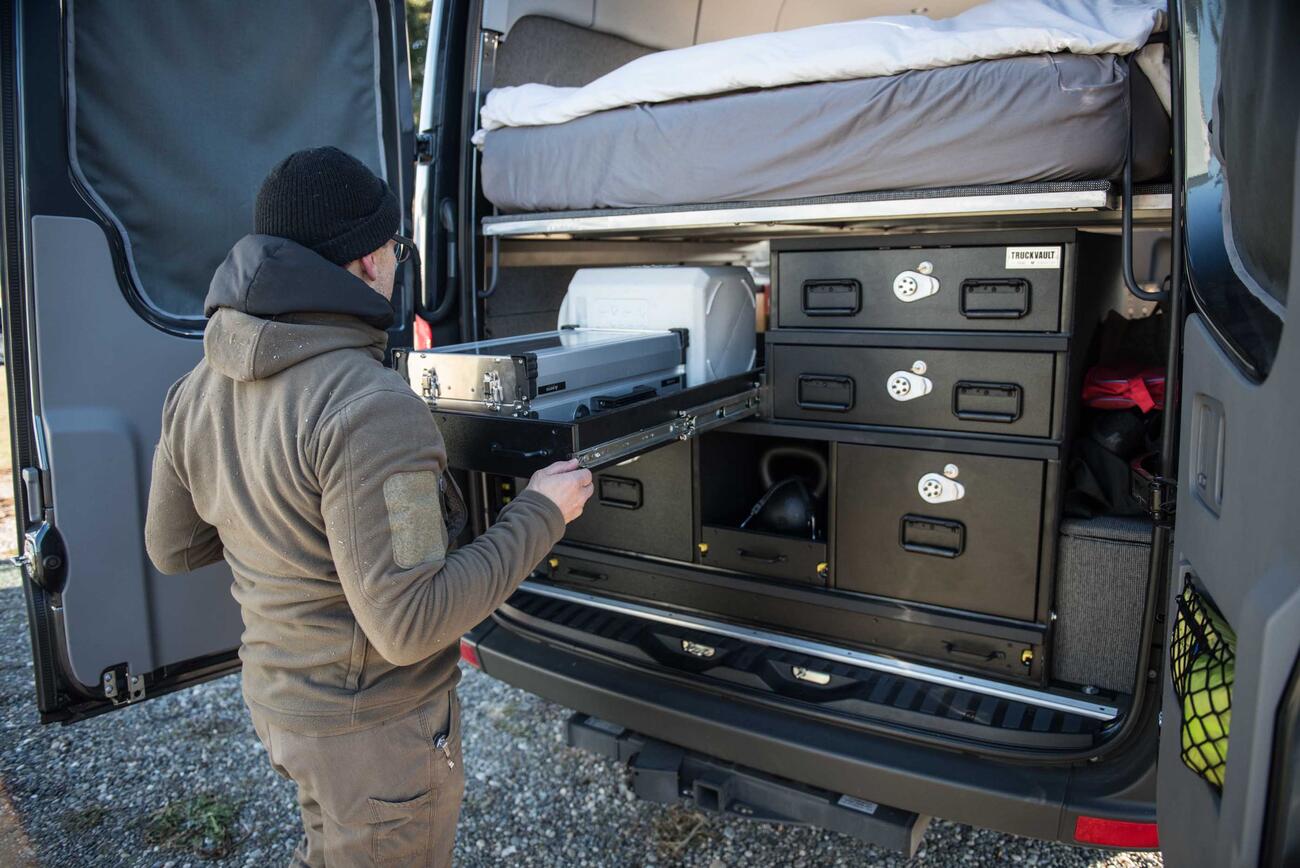 A man opening a custom TruckVault storage system in a Mercedes Sprinter van.