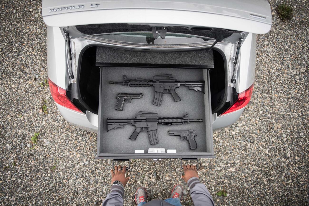 TrunkVault-7.jpg A silver Chevy Impala with a person pulling out a TruckVault drawer with guns.