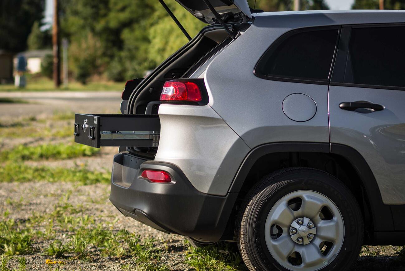 A Jeep Grand Cherokee parked with a TruckVault opening out of the rear.