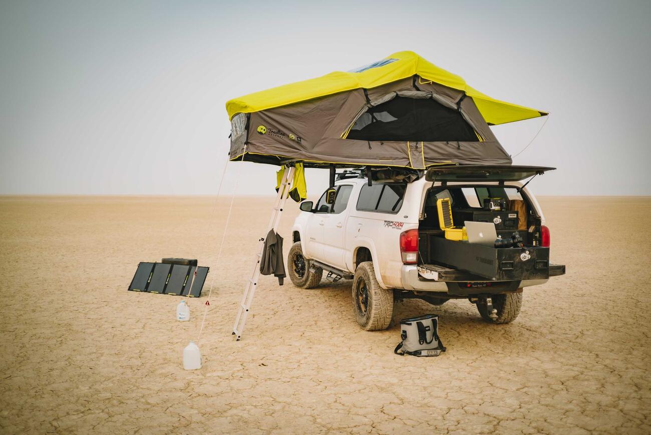 A white truck parked in a desert with an open TruckVault in the back