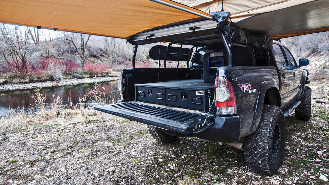 A Toyota Tundra with a TruckVault secure storage system in the bed and a rooftop tent 