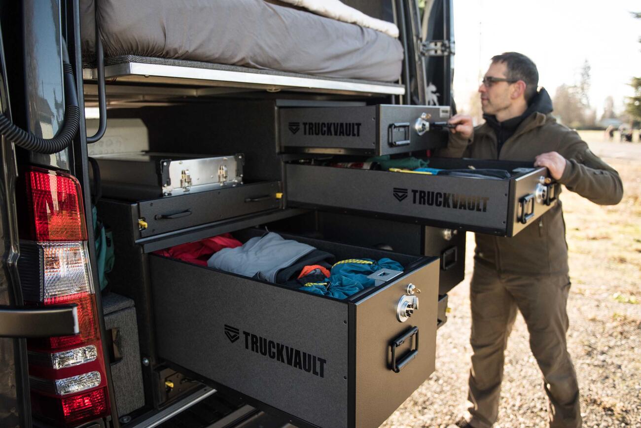 A man rummaging through his TruckVault secure storage system in the back of a Mercedes Sprinter