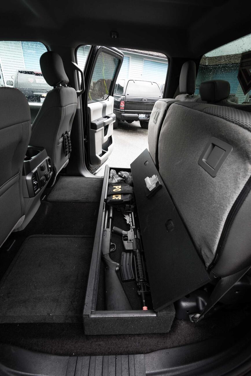 An open SeatVault in the back of a Ford F150 with guns and other police gear.