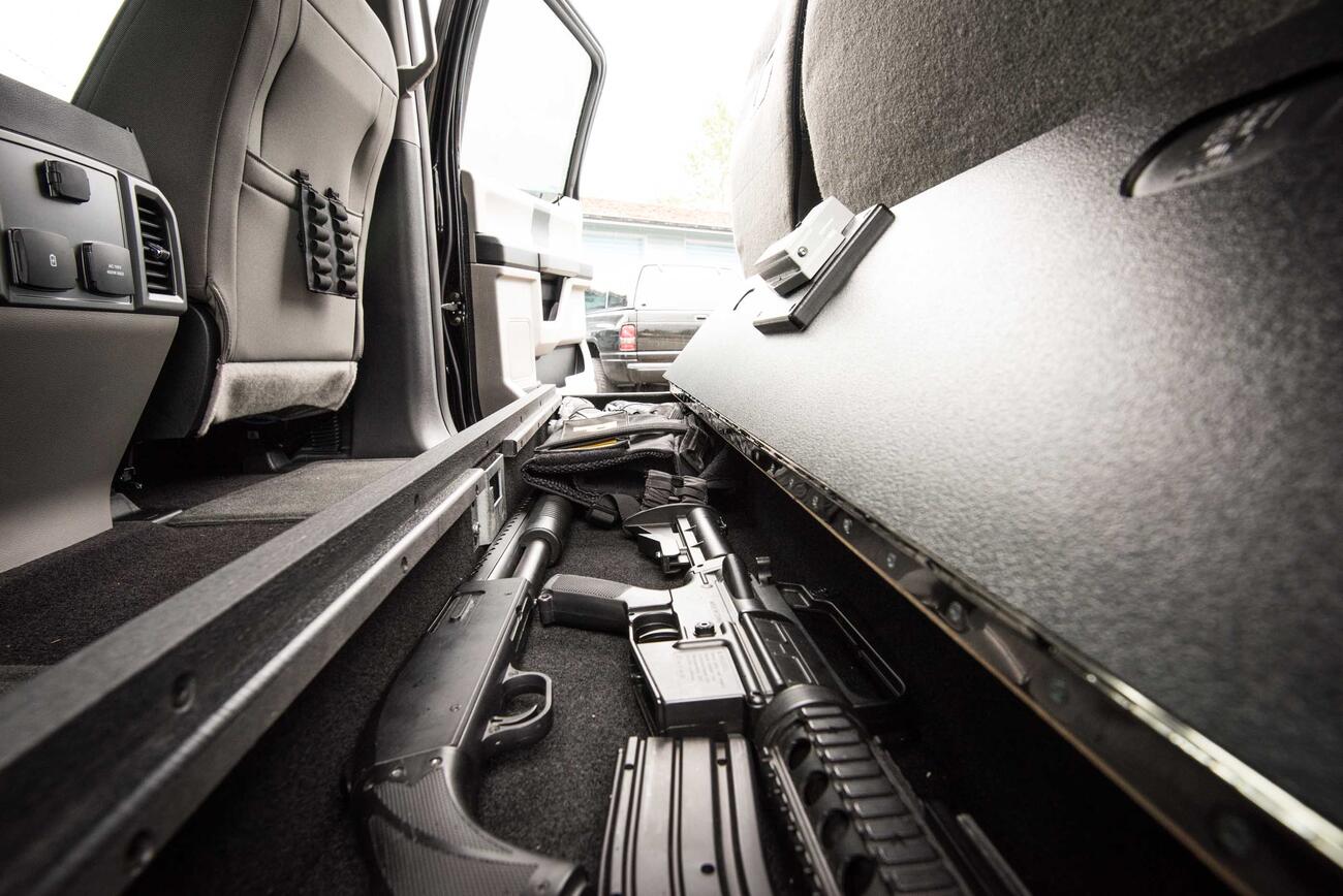 An open SeatVault in the back of a Ford F150 with guns and other police gear.