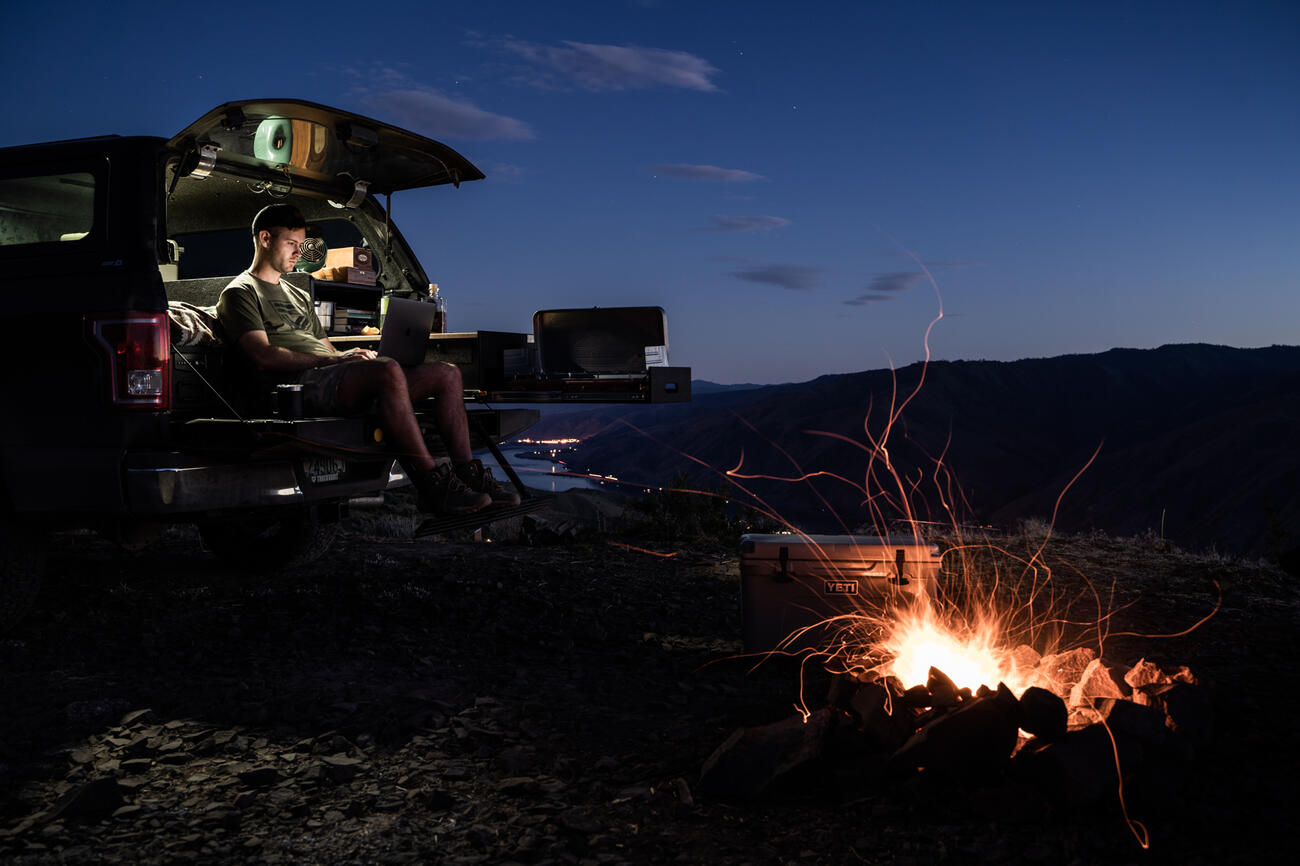 Working on laptop by fire out of TruckVault Base Camp 5