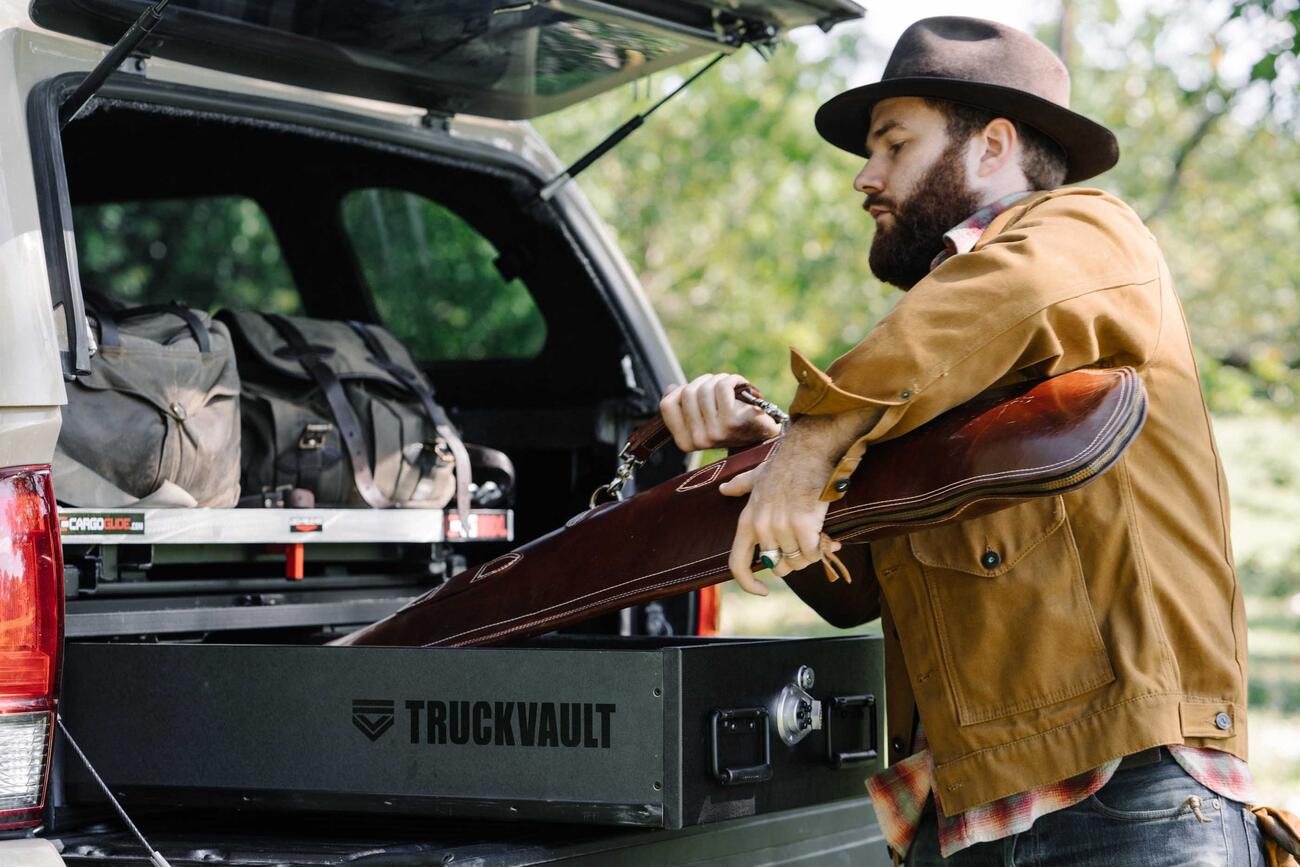 PickupSeries_CoveredBedLine_Standard2Drawer_2016_Toyota_Tacoma_TylerSharp3.jpg A man placing his shotgun into his TruckVault