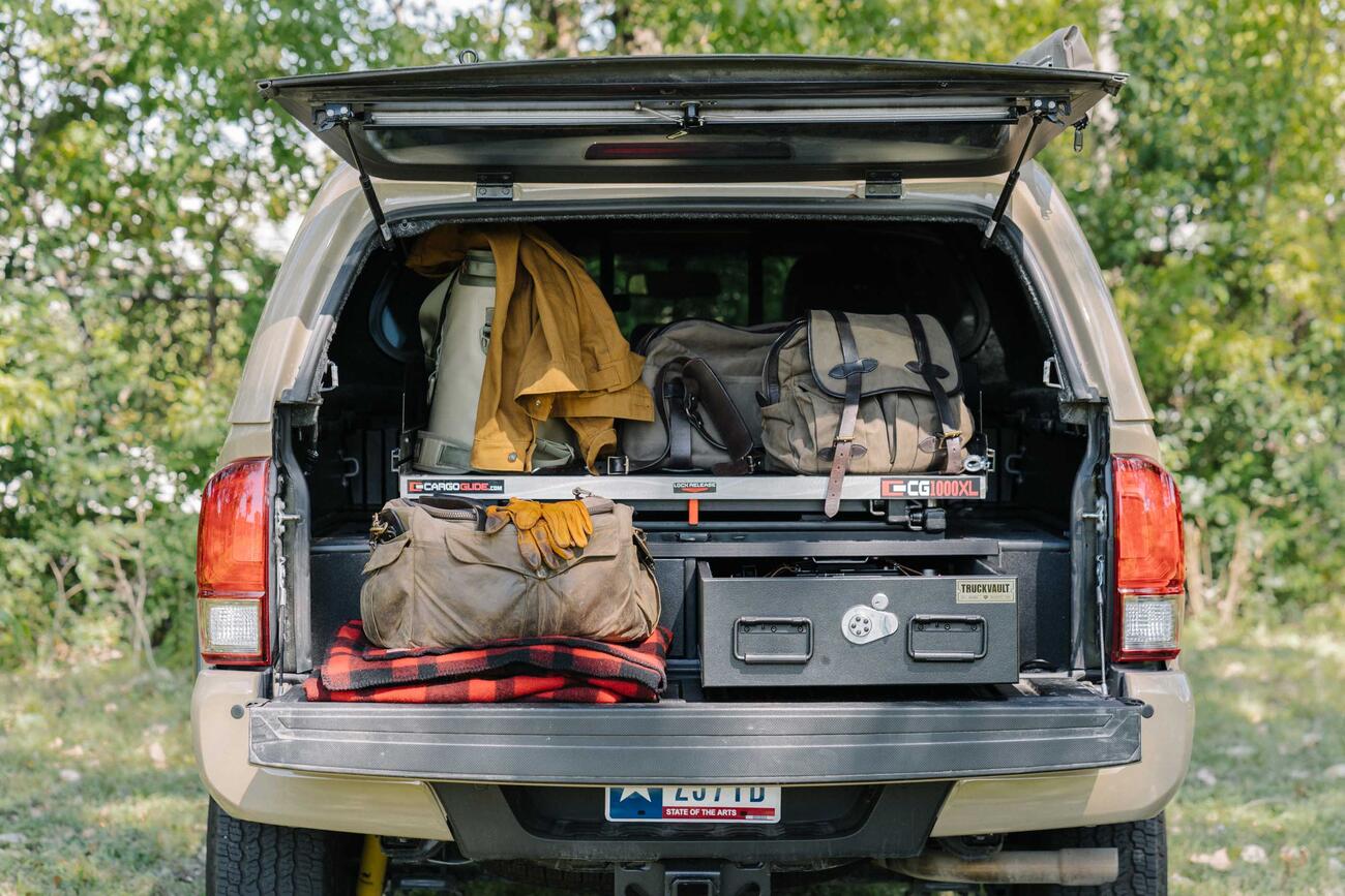 A truck with a canopy and a TruckVualt and a Cargo Glide in the the back. The truck bed area is full of gear, in and on the TruckVault.