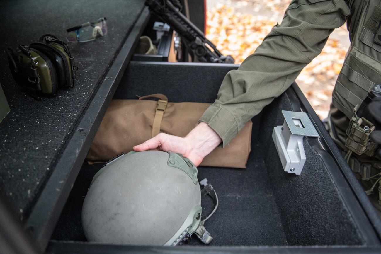  A man grabbing a helmet out of a TruckVault drawer in the back of a Chevy Tahoe.