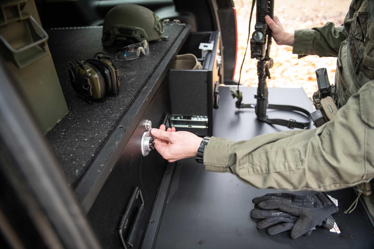 A man opening a TruckVault while resting his gun a heavy duty pull out table.