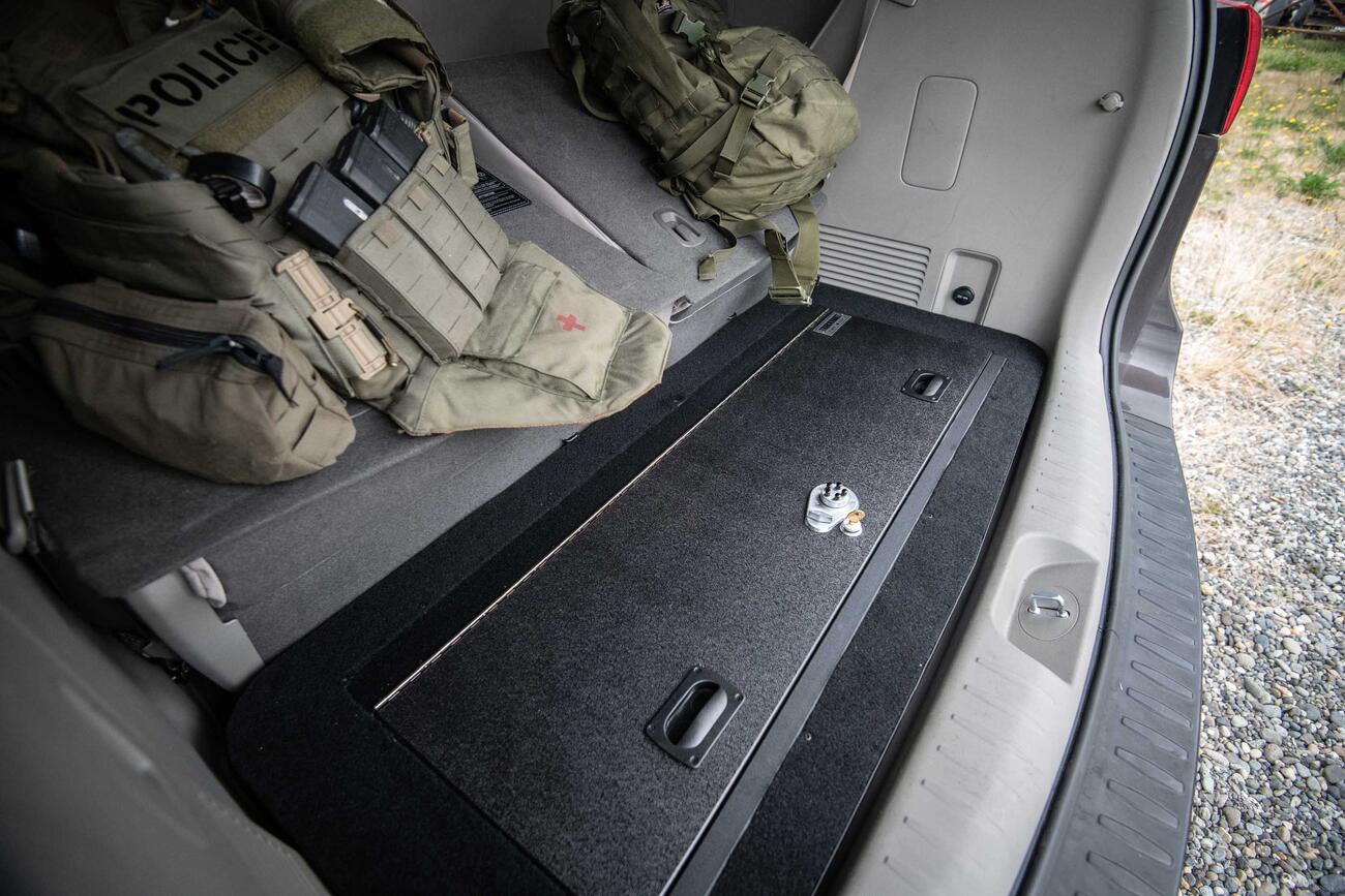 A Kia Sedona FloorVault next to two police backpacks.