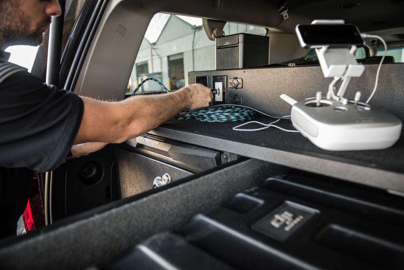 A police officer plugging his drone into his TruckVault technology platform.