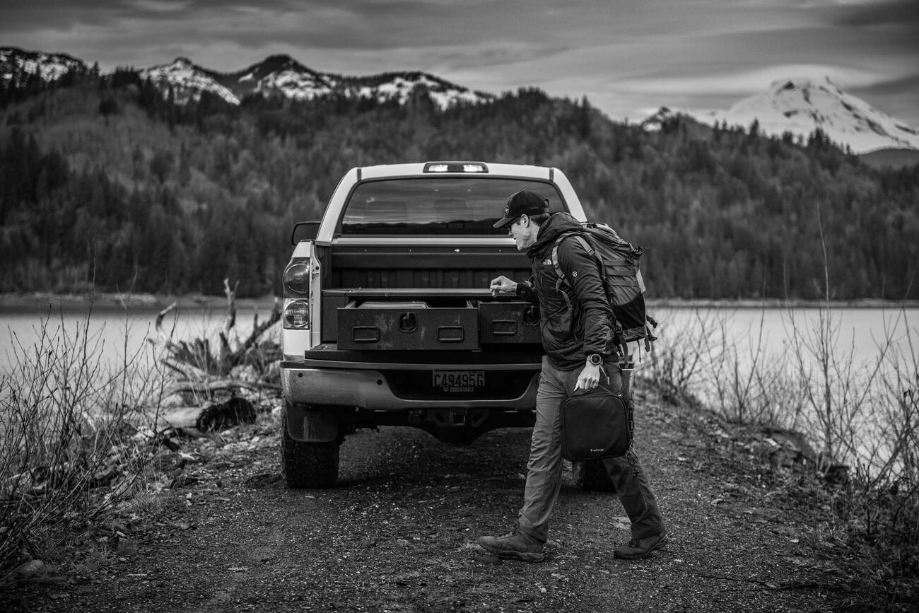 A man with a backpack walking past a Toyota Tundra with a TruckVault in the bed.