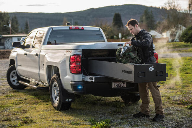 A man standing at the back of his pickup, putting gear into his TruckVault.