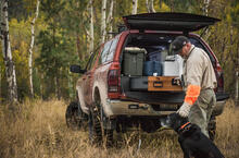 A man petting his dog while standing in front of his wood drawer front TruckVault.