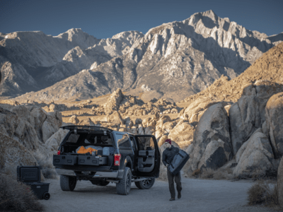 outdoorsman paking gear into drawer of TruckVault secure truck bed storage system for covered pickup trucks with mountains in background