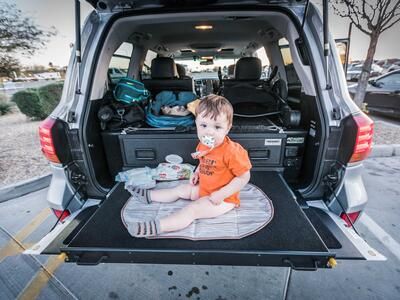 A baby sitting on a heavy duty pull out table in a Lexus LX570.