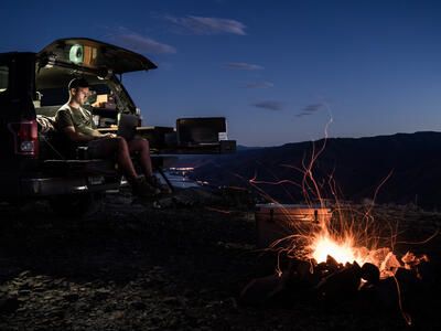 Working on laptop by fire out of TruckVault Base Camp 5