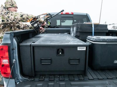 A man in camouflage placing his bow on top of a Half Width TruckVault.