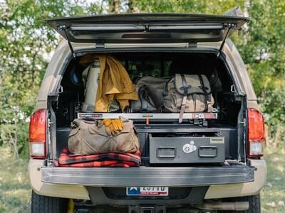 A truck with a canopy and a TruckVualt and a Cargo Glide in the the back. The truck bed area is full of gear, in and on the TruckVault.