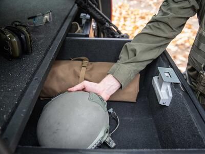  A man grabbing a helmet out of a TruckVault drawer in the back of a Chevy Tahoe.