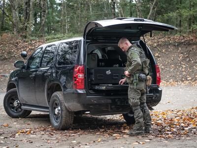 A man loads his magazine on a heavy duty pull out table in the back of a Chevy Tahoe.