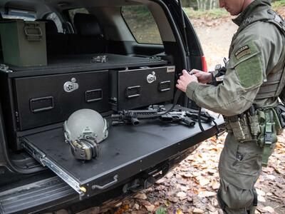 A SWAT officer working on his gun on a heavy duty pull out table on a TruckVault in the back of Chevy Tahoe.