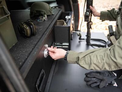 A man opening a TruckVault while resting his gun a heavy duty pull out table.