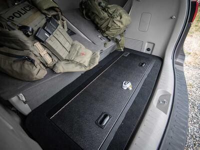 A Kia Sedona FloorVault next to two police backpacks.