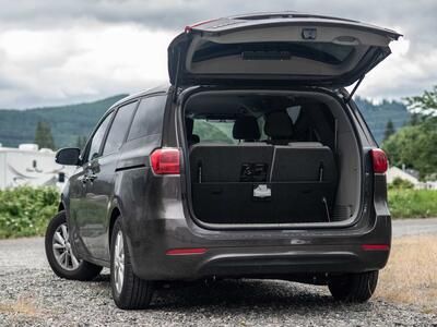 The back side of a black KiaSedona with an open trunk and an open FloorVault.