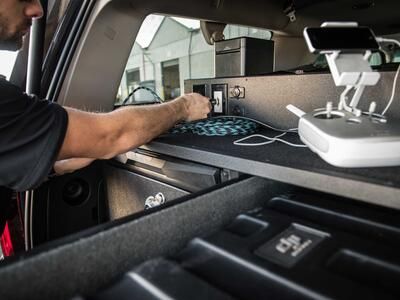 A police officer plugging his drone into his TruckVault technology platform.