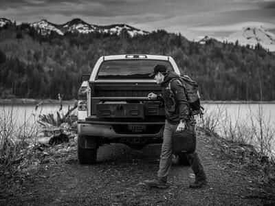 A man with a backpack walking past a Toyota Tundra with a TruckVault in the bed.