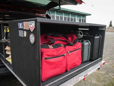 A custom Truckvault in the back of a red Chevy Suburban filled with fire fighting gear.